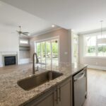 Bright and modern kitchen interior featuring granite countertops, wooden flooring, and ample natural light.
